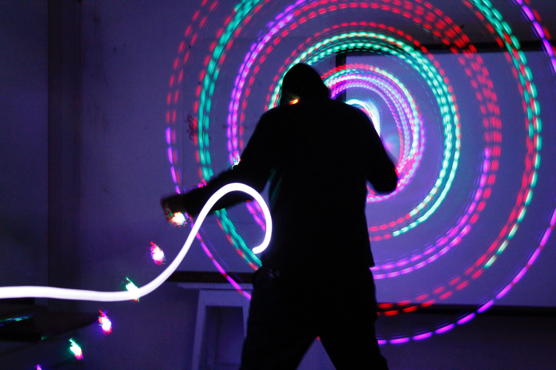 Silhouette of a person standing in front of coloured lights arranged in concentric circles