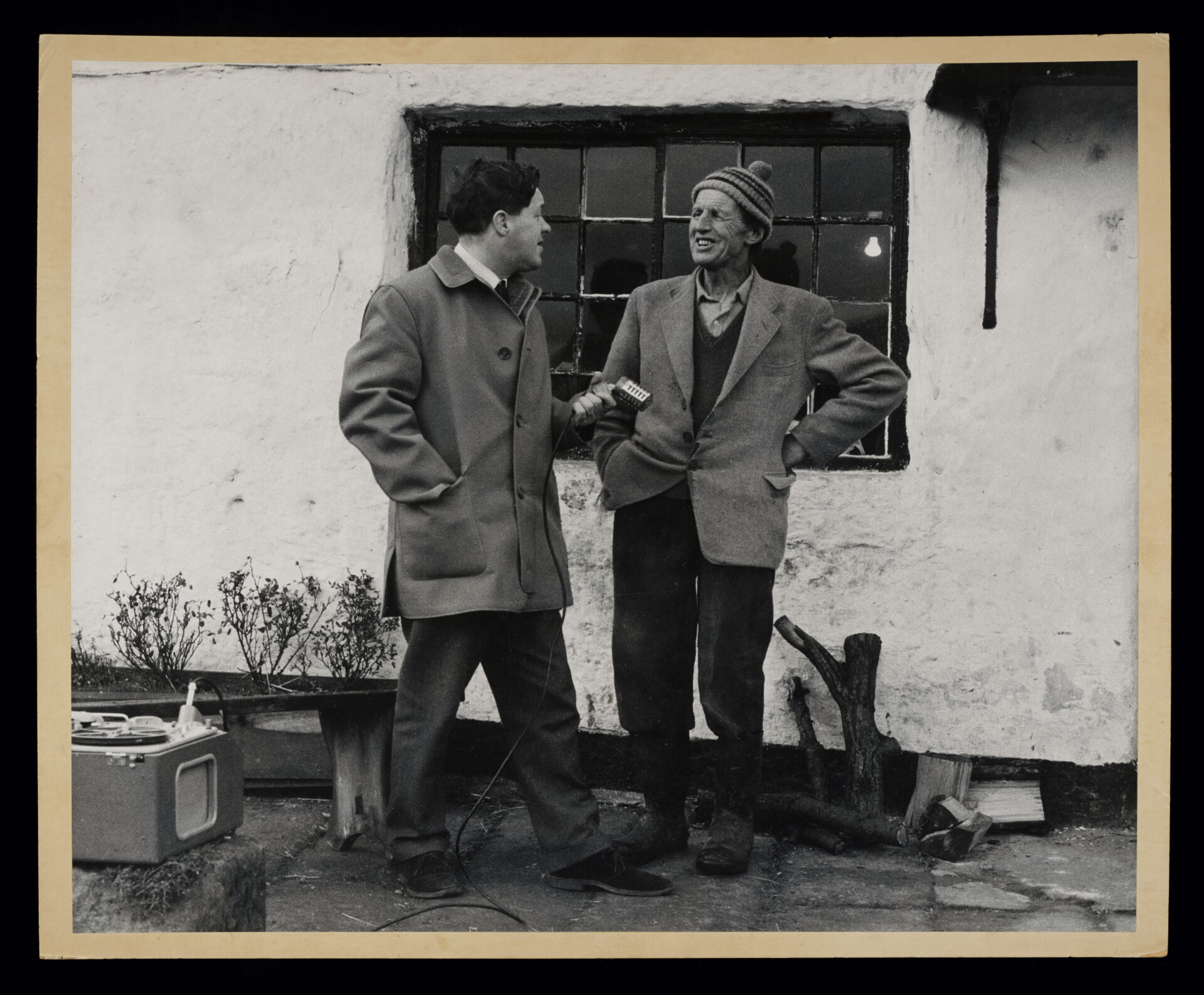 Stanley Ellis and Tom Mason recording their conversation outside. They are stood in front of a house. 