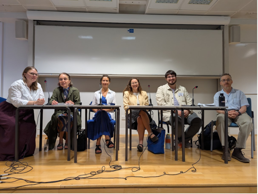 6 participants in the round table seated at a table with microphones